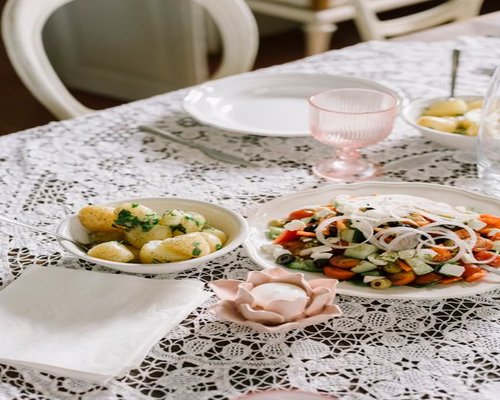 A well-lit Mediterranean dining table with fresh salad, olive oil, and a glass of water