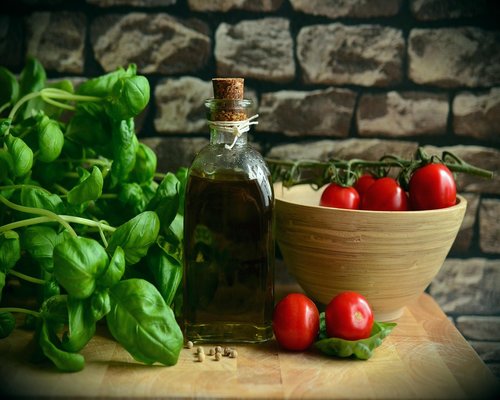 Assortment of fresh local vegetables, legumes, and olive oil on a wooden kitchen counter