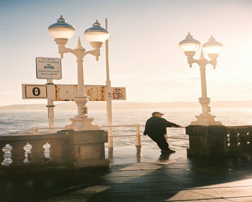 Man walking leisurely on a seaside promenade in the late afternoon
